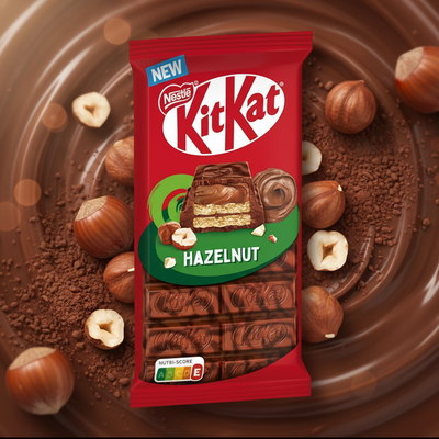KitKat Hazelnut chocolate bar packaging on a chocolate background with hazelnuts.