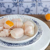 Dumplings with a yellow filling on a decorative plate with a blue and white patterned tile background.