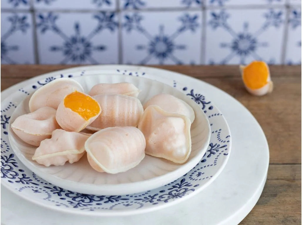 Dumplings with a yellow filling on a decorative plate with a blue and white patterned tile background.