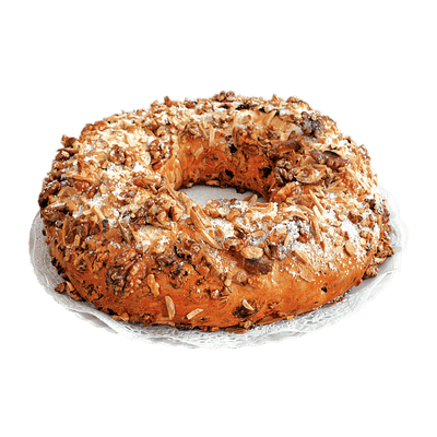 A round, multi-layered cake dusted with powdered sugar, decorated with nuts and fruits, and placed on a plate.