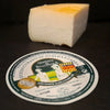 Block of cheese with a label on a dark surface