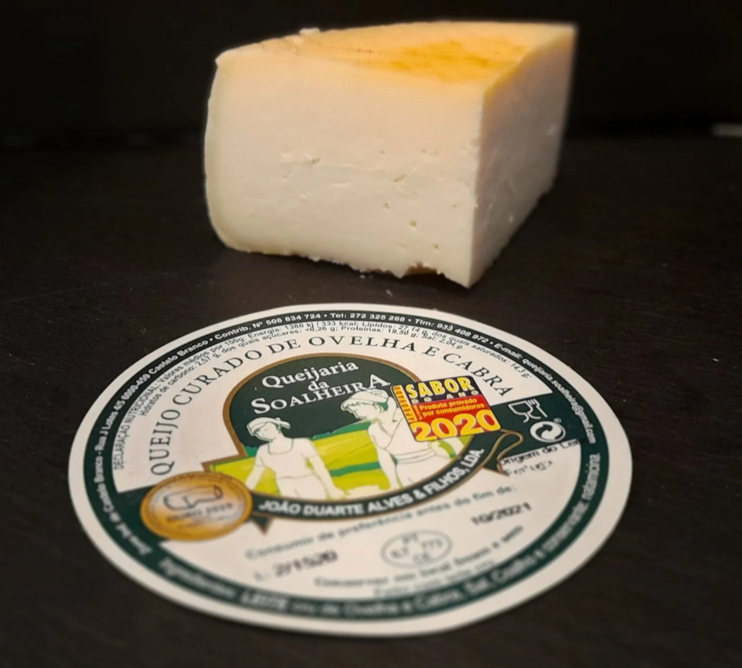 Block of cheese with a label on a dark surface